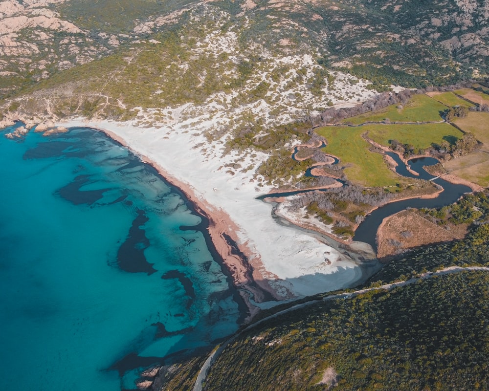 aerial view of green and brown land near blue body of water during daytime