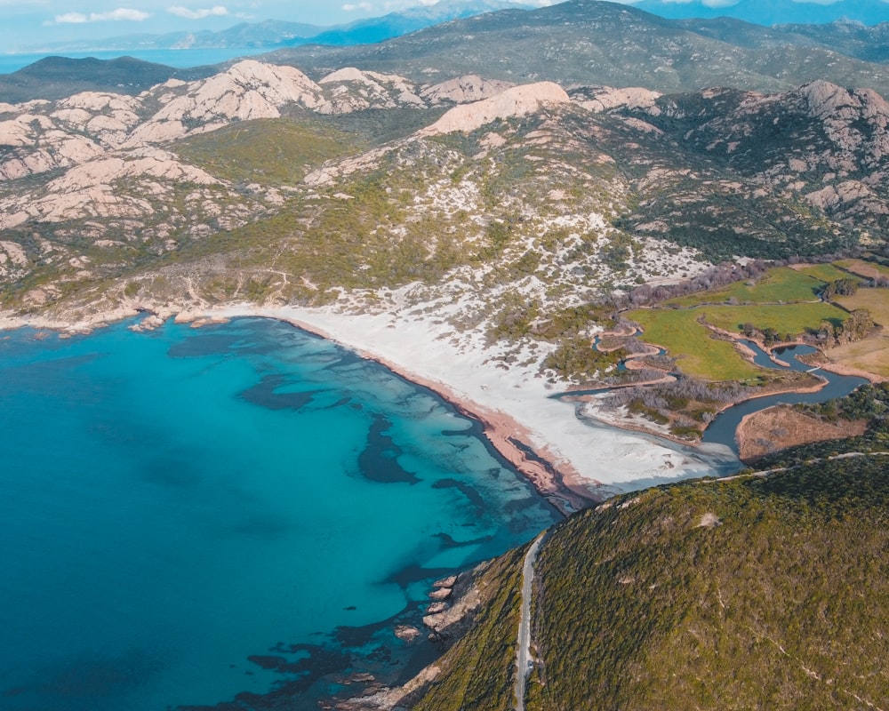 aerial view of green and brown mountains and blue sea during daytime