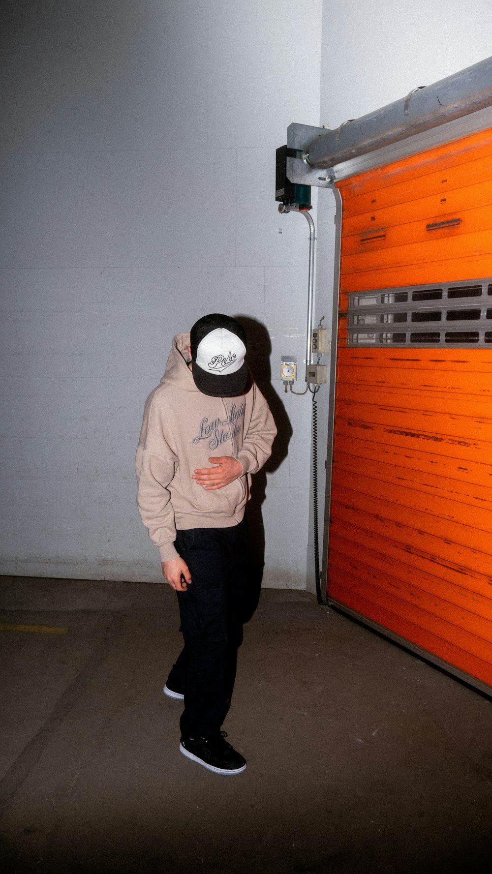 man in gray hoodie standing near white wall