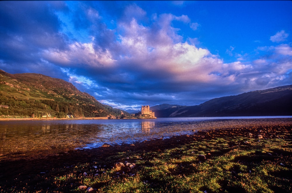 brown concrete building on body of water under blue sky and white clouds during daytime