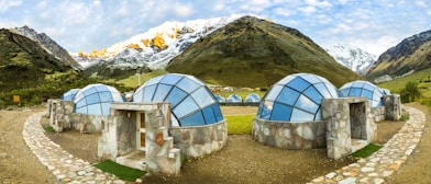 white and blue dome tent on green grass field near mountain during daytime