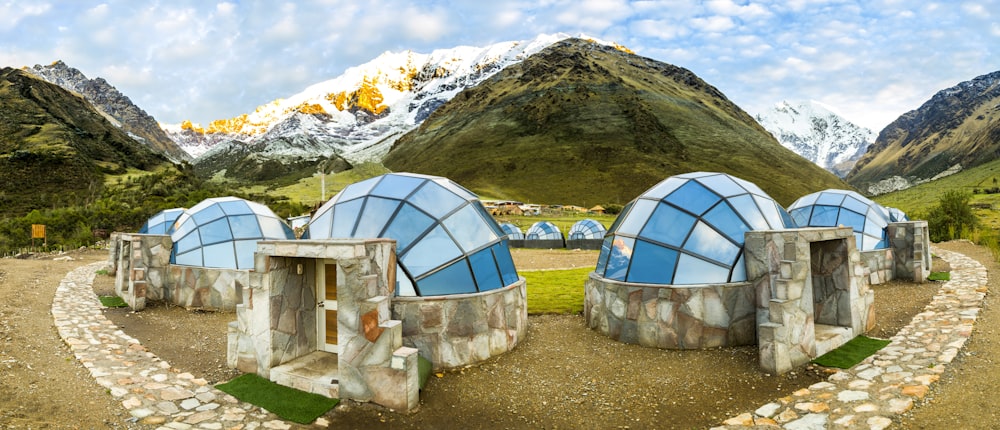 white and blue dome tent on green grass field near mountain during daytime