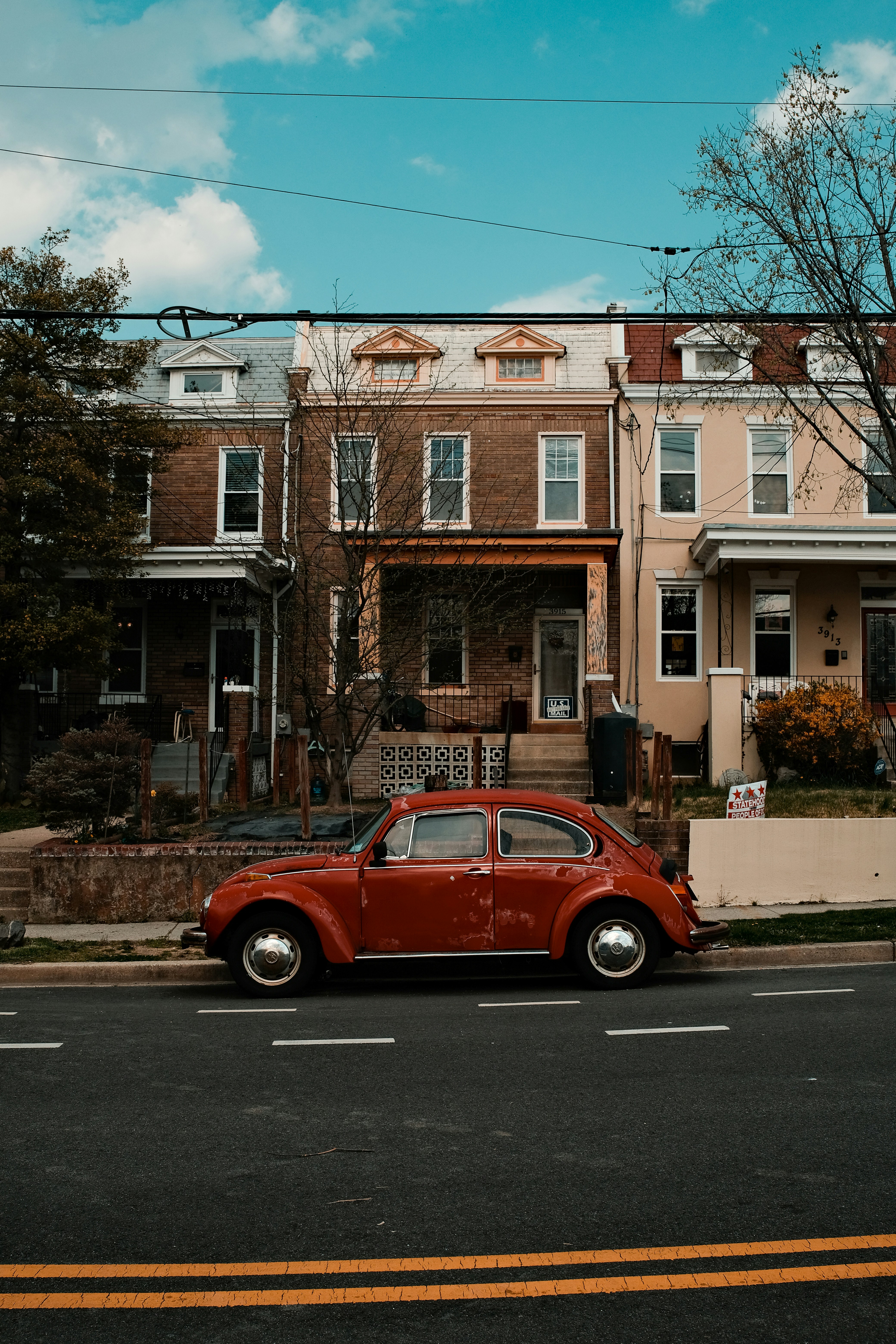 Coche rojo estacionado junto al edificio de hormigón marrón durante el día