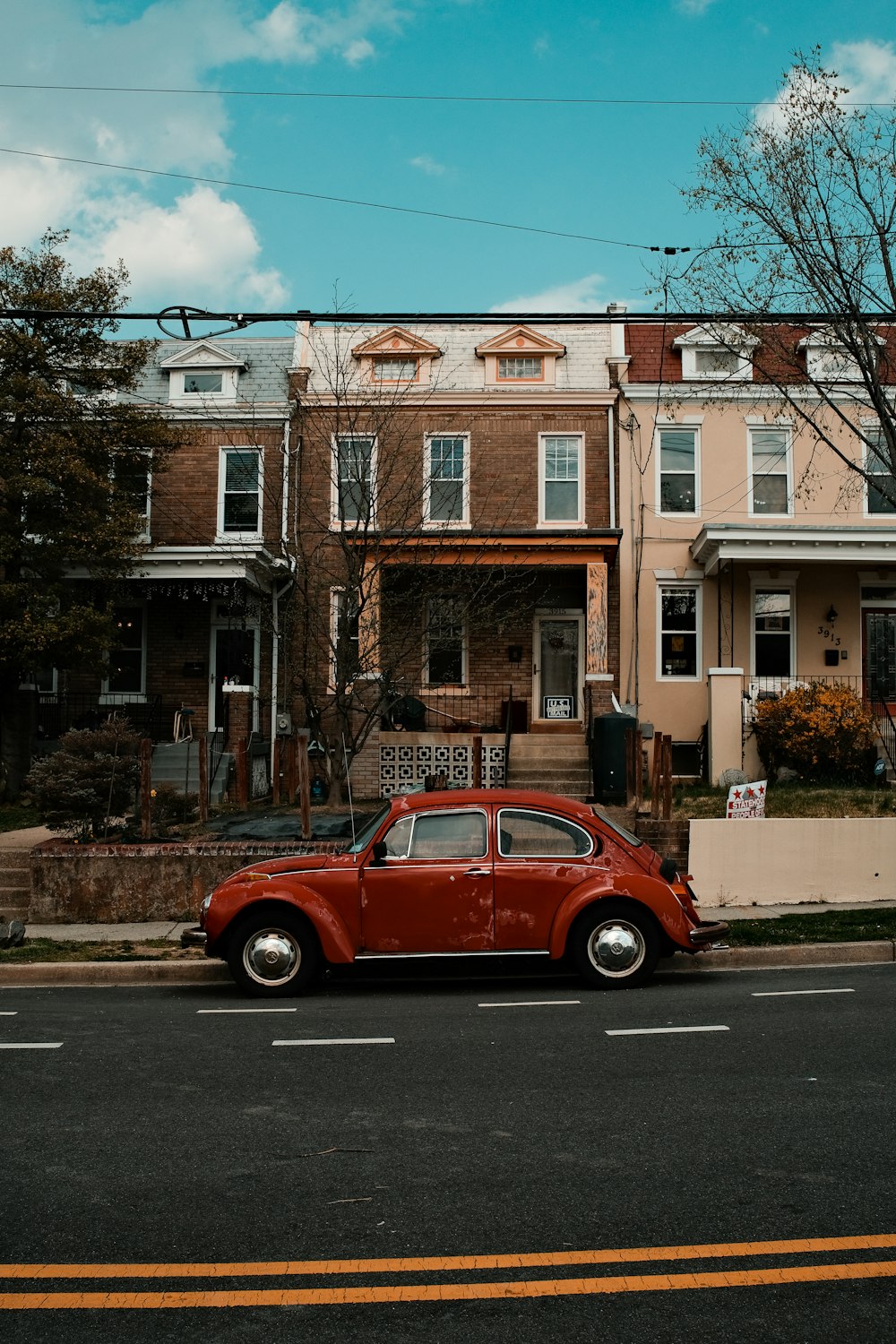 red car parked beside brown concrete building during daytime