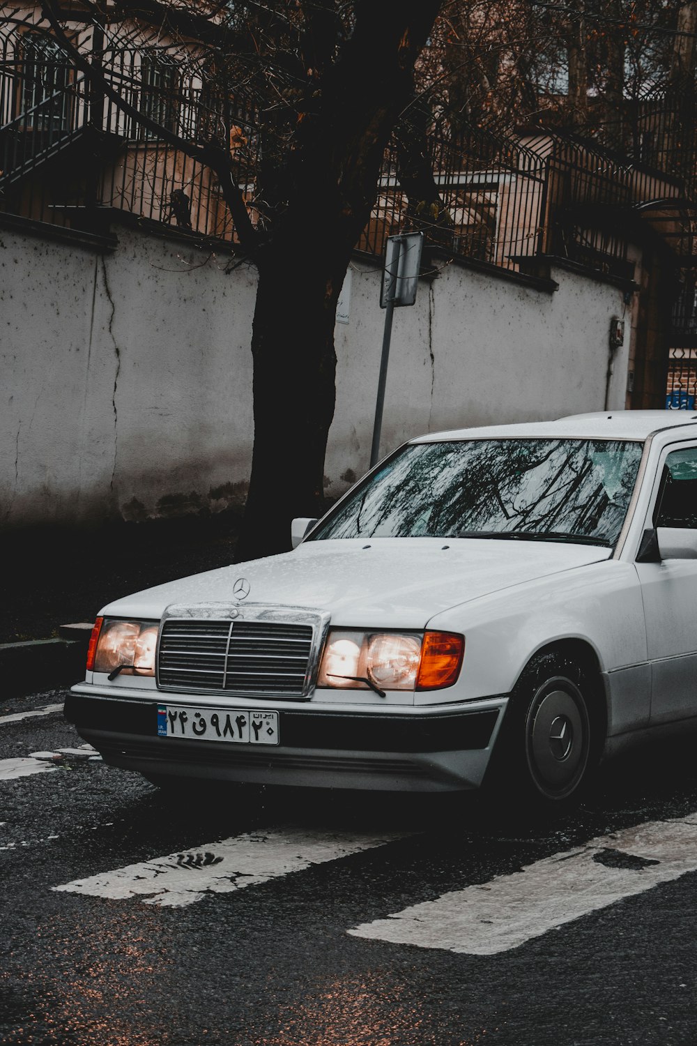 white sedan parked beside gray concrete wall