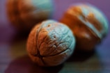 Close-up view of walnuts with detailed textures and a shallow depth of field, creating a smooth, blurred background. The lighting casts a warm and slightly bluish hue over the image.