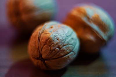 Close-up view of walnuts with detailed textures and a shallow depth of field, creating a smooth, blurred background. The lighting casts a warm and slightly bluish hue over the image.