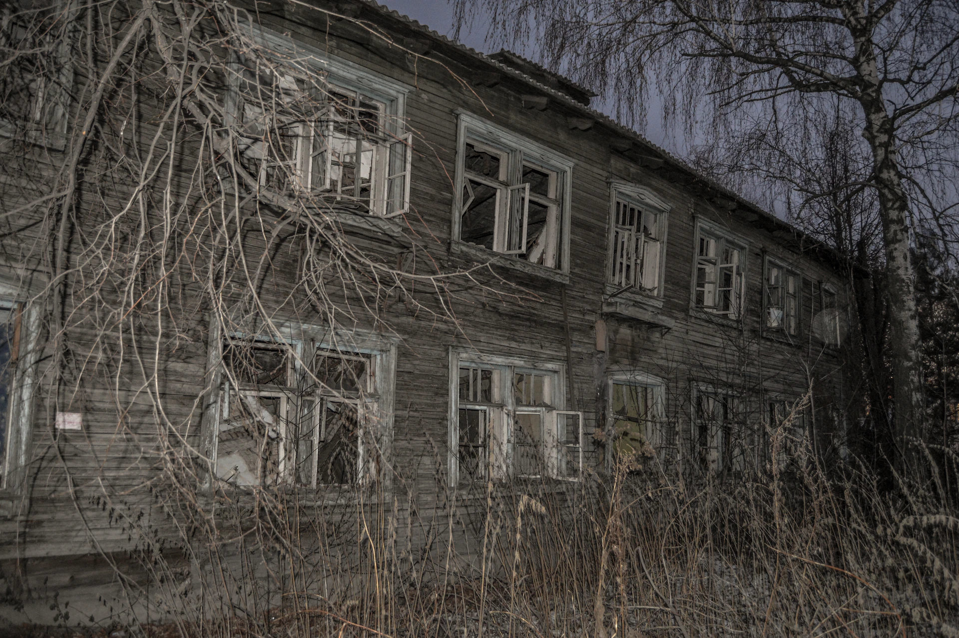 A misty, eerie shot of an abandoned building with broken windows and overgrown vines, capturing the haunted vibe of viajante sombrío's explorations.