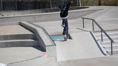 A skate instructor demonstrating a trick on a smooth boardwalk.