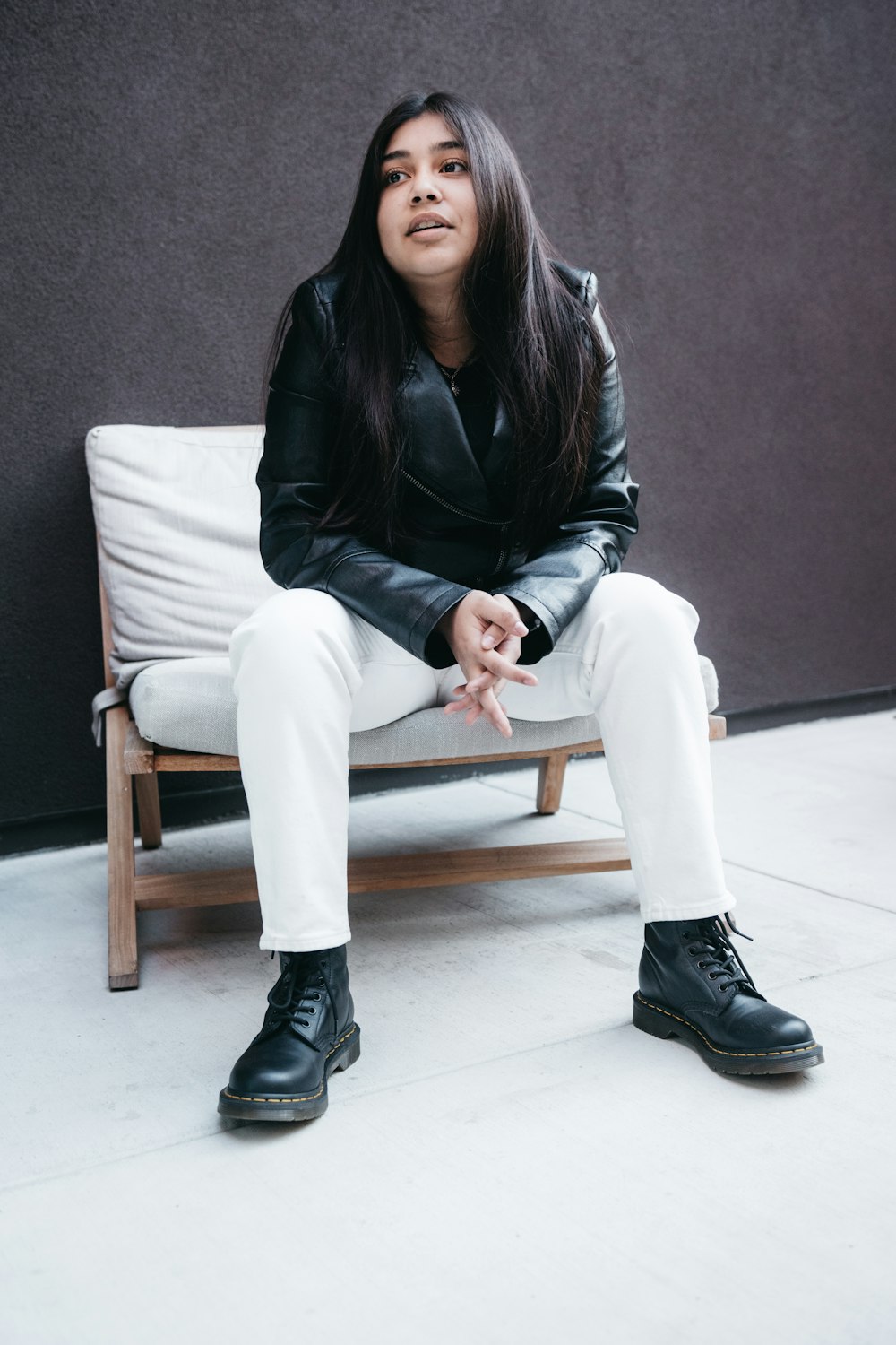 woman in black leather jacket sitting on brown wooden armchair
