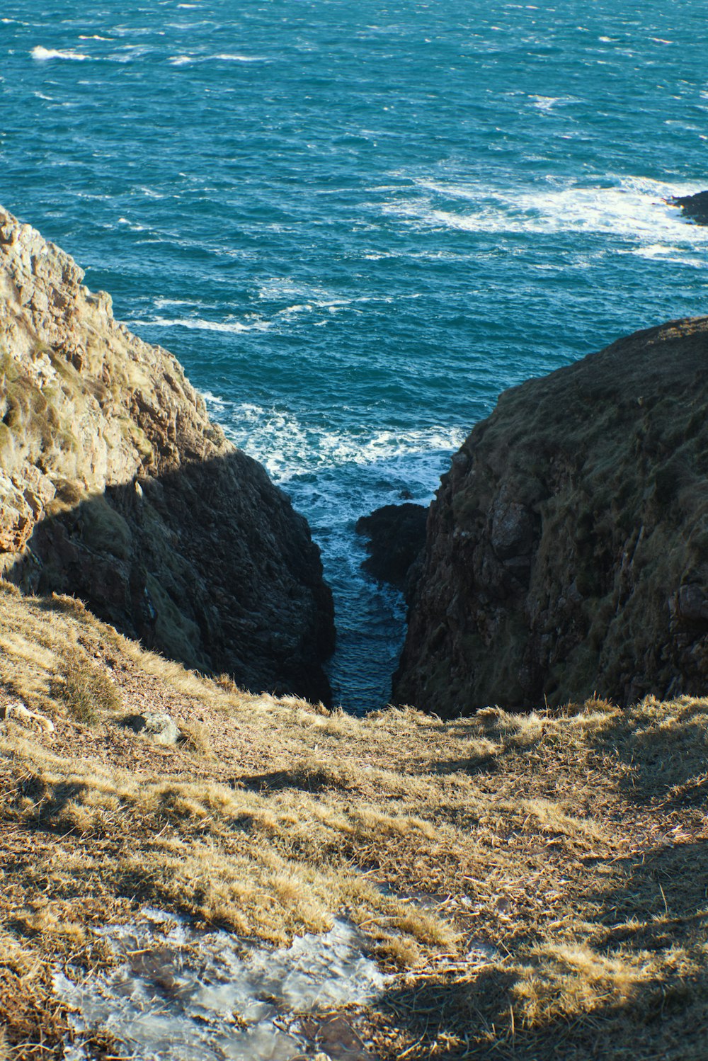 brown rocky mountain beside blue sea during daytime