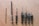 Seven drill bits of varying sizes are lined up on a wooden surface. The bits have a metallic sheen and appear to be well-used, with some showing signs of wear.
