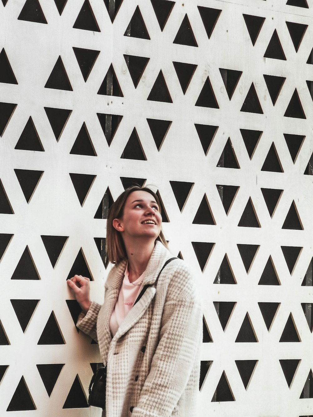 woman in white knit sweater standing beside white wall