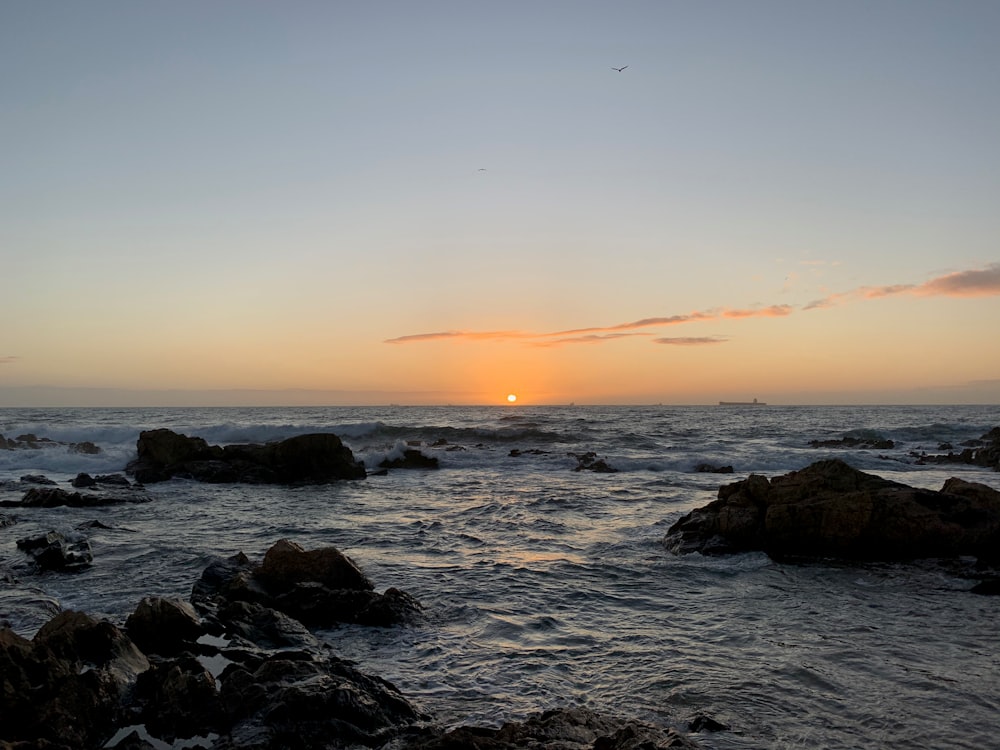 日没時に海岸に波が打ち寄せる岩だらけの海岸