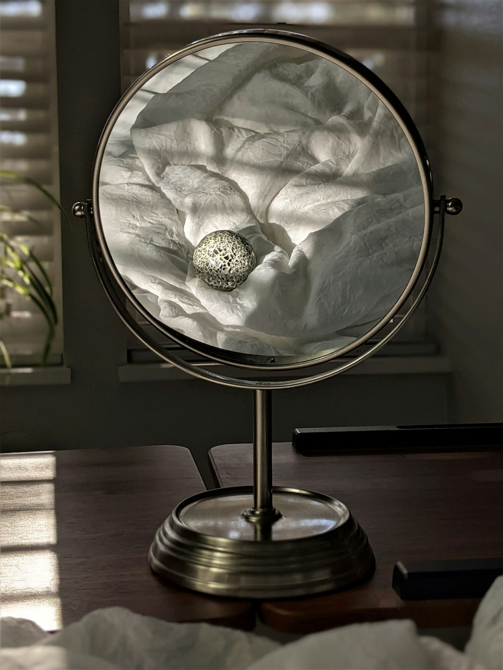 silver round mirror on brown wooden table