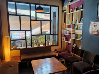 A candid photo of people enjoying a cozy indoor reading space with soft sand tones and terracotta accents.