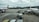 Airplanes are parked on an airport tarmac with airport ground handling vehicles and personnel around them. One plane has a colorful livery promoting 'Sustainable ASEAN Tourism', while another displays airline branding. The scene includes overcast skies and distant background buildings.