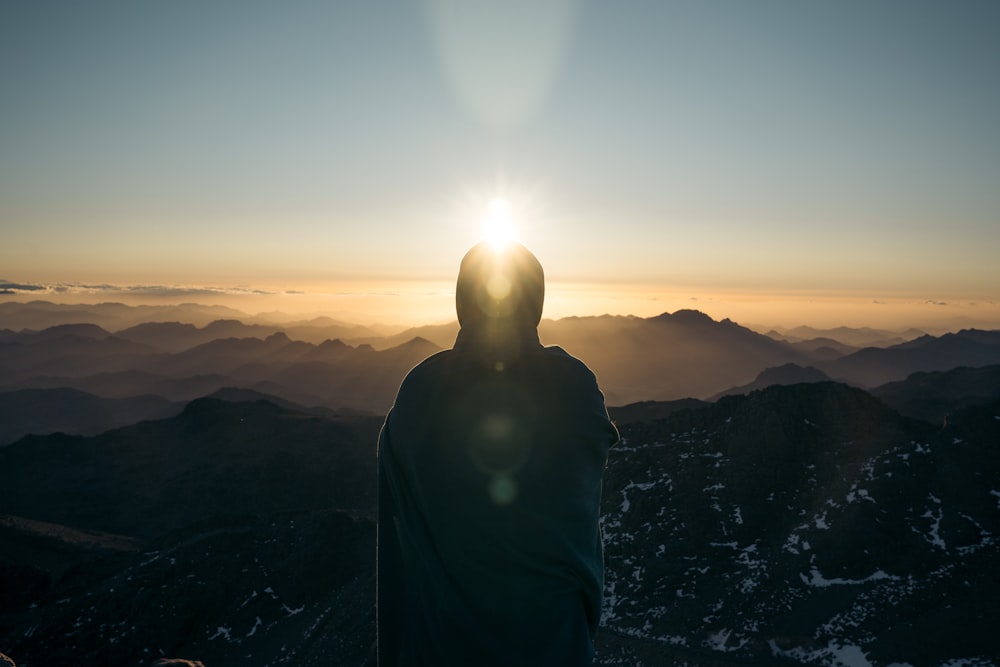 man in black jacket standing on mountain during daytime
