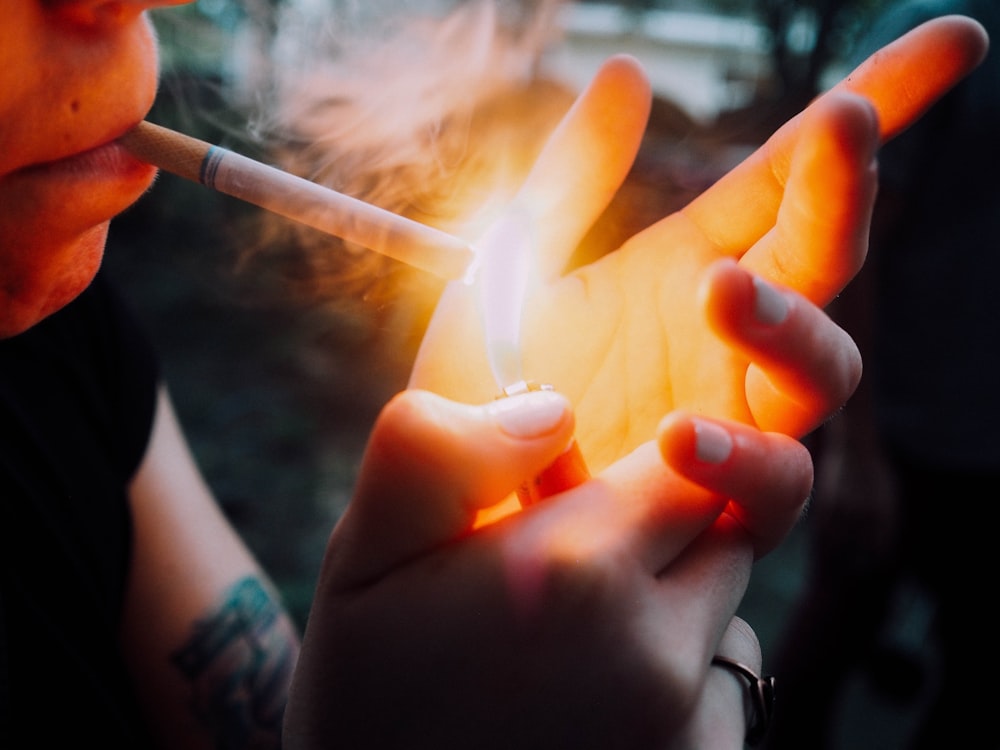 person holding lighted cigarette stick