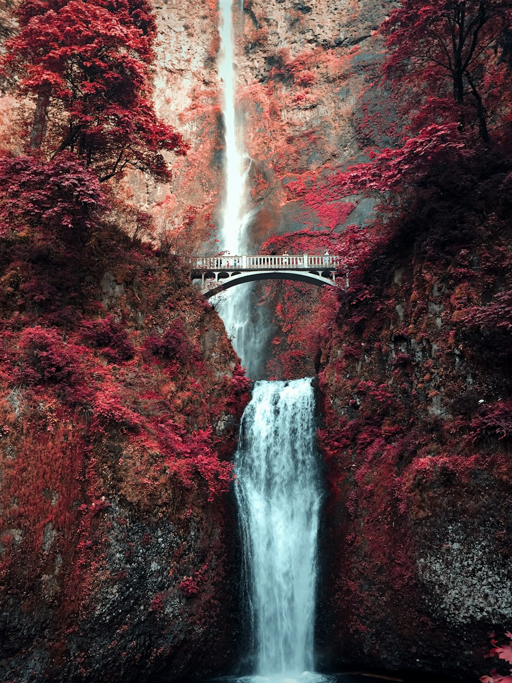 white bridge over waterfalls during daytime