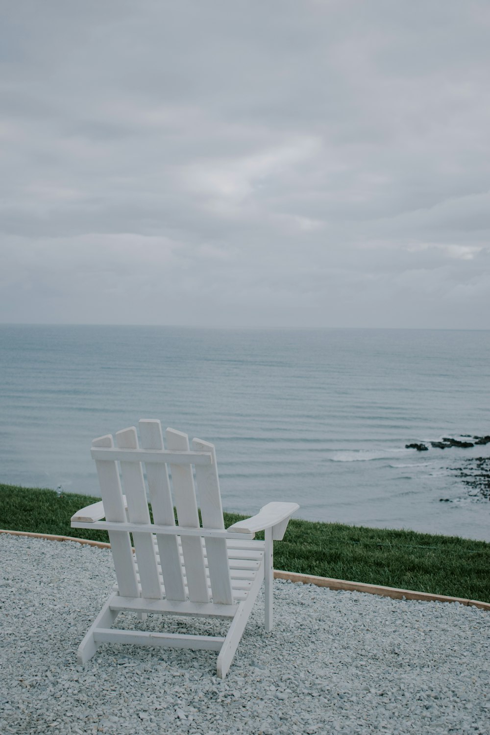 white plastic armchair on gray concrete floor near body of water during daytime