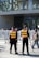 Two security personnel wearing reflective vests stand in front of a crowd, near barricades, outside the Shanghai Natural History Museum. The scene is busy with many people around, and the building's glass facade and signage are visible.