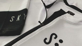 Close-up of a sleek black sports jacket with subtle reflective details on a minimalist white background