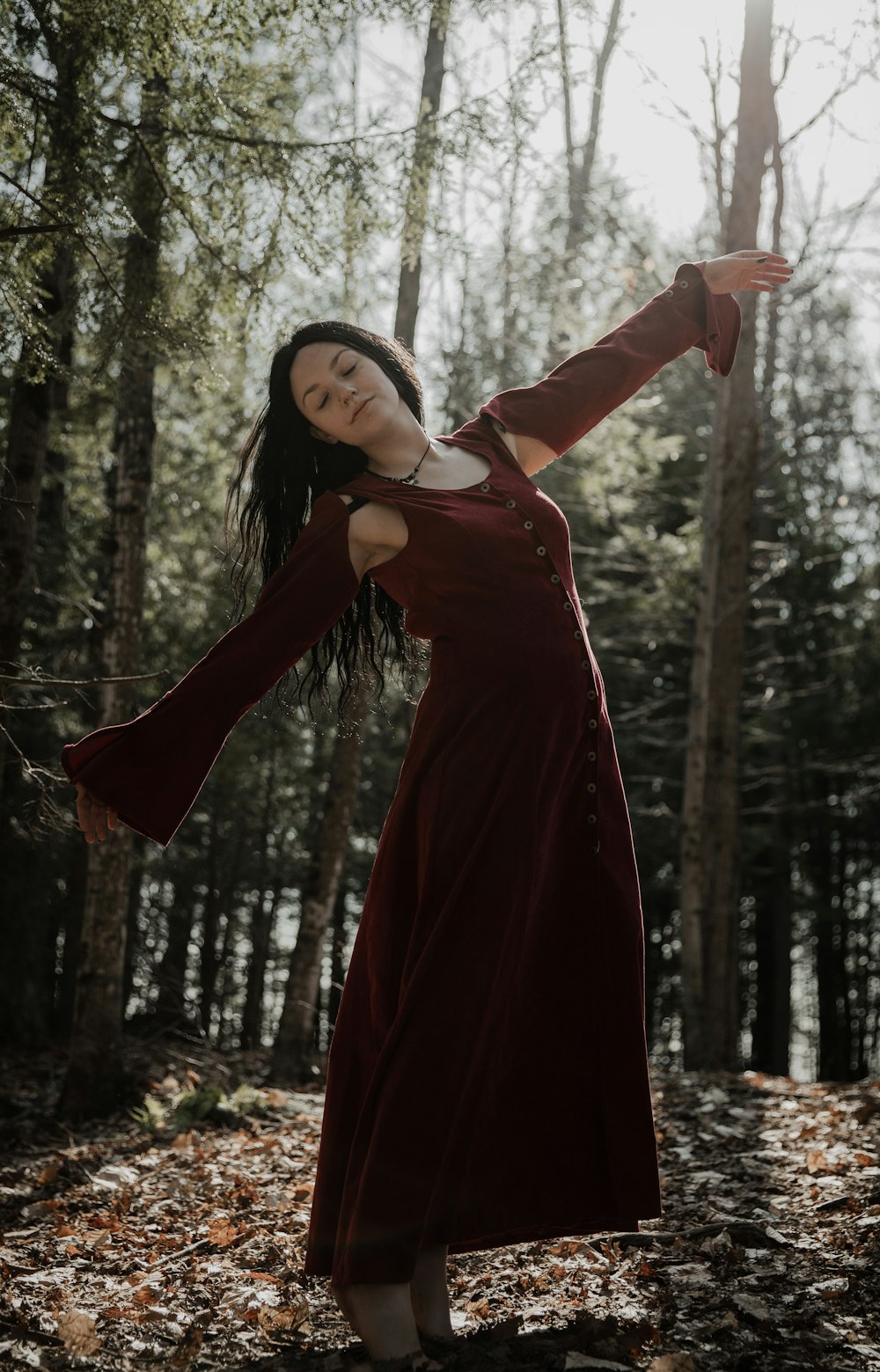 woman in red long sleeve dress standing in forest during daytime