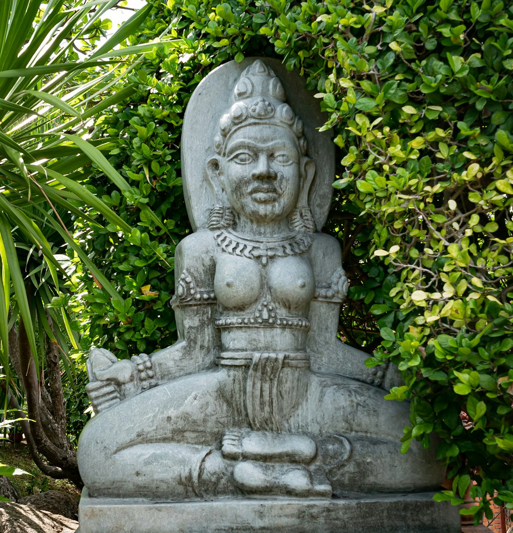 gray concrete statue surrounded by green plants