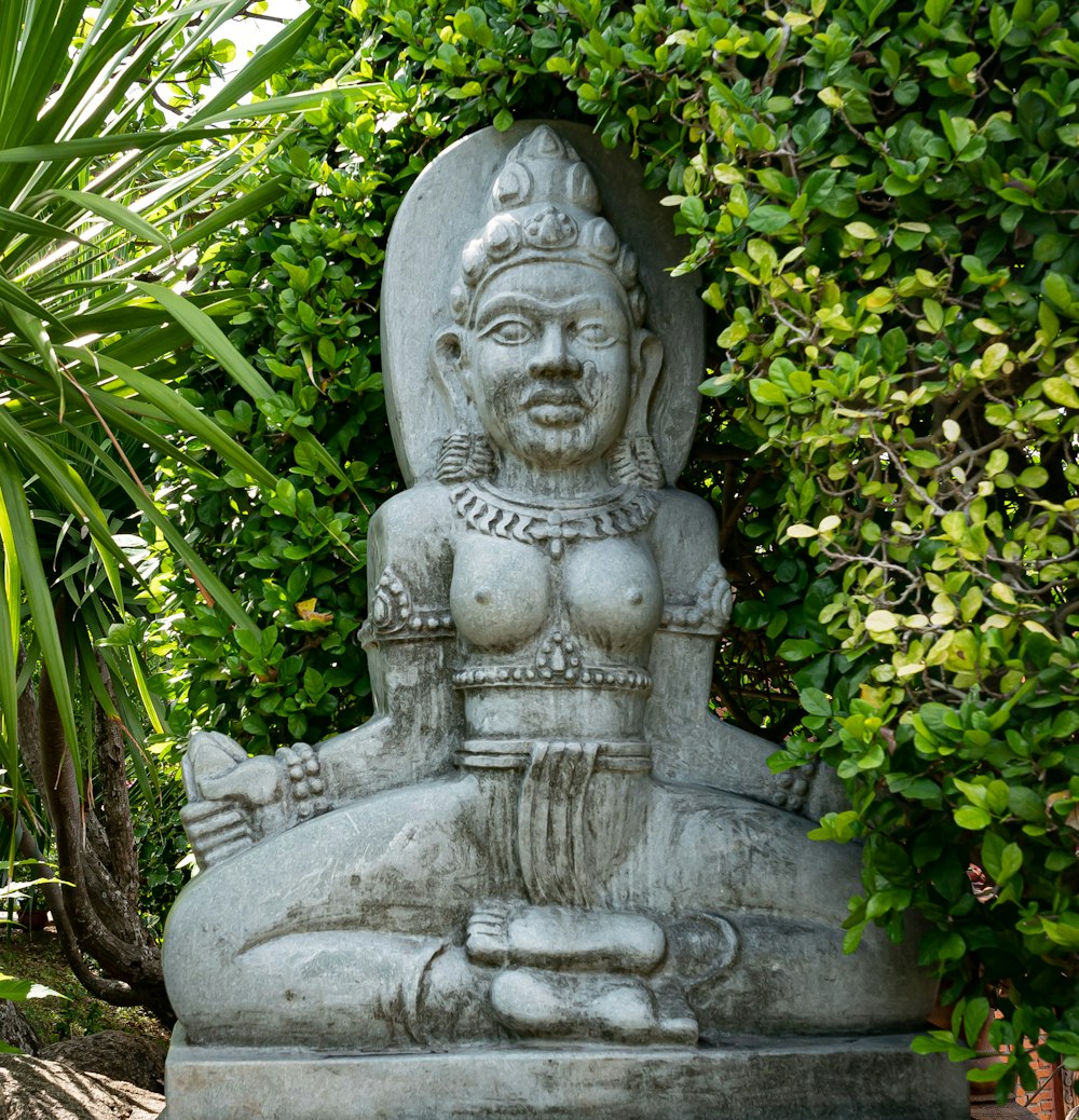 Statue en béton gris entourée de plantes vertes