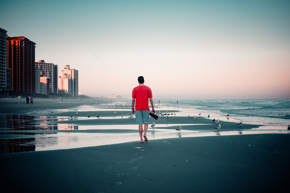 Hombre con sudadera con capucha roja de pie en la playa durante el día