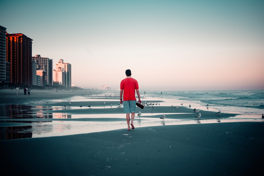 man in red hoodie standing on beach during daytime