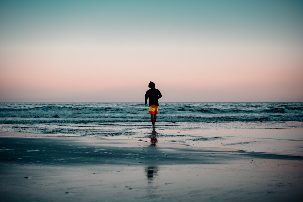 man in black jacket walking on beach during daytime