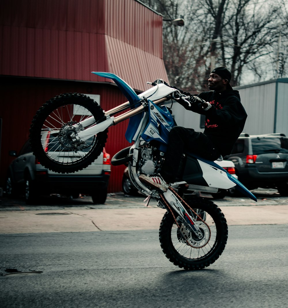青いモトクロスダートバイクに乗る黒いジャケットの男