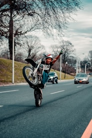 man in black and white motorcycle suit riding on motorcycle on road during daytime