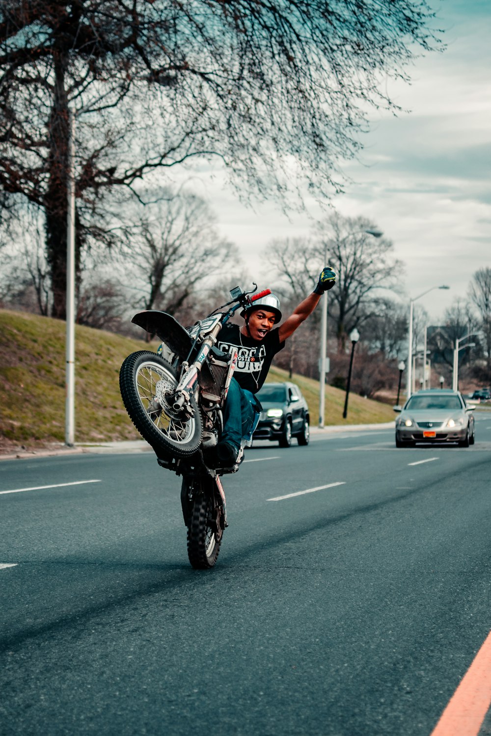 昼間に道路でバイクに乗る白黒のオートバイスーツを着た男性
