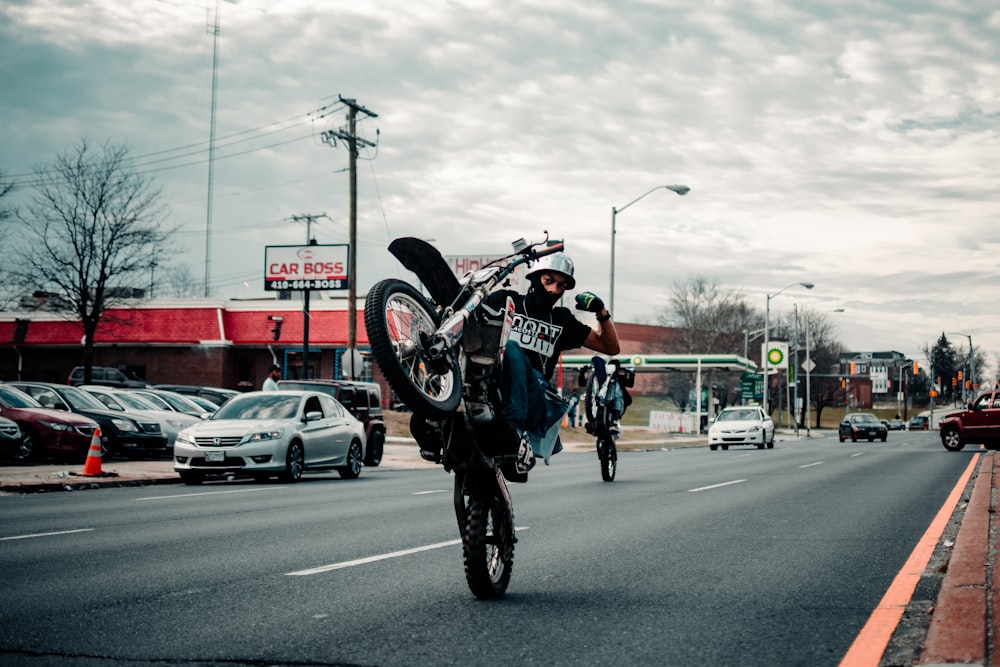 赤と黒のオートバイスーツを着た男性が昼間に道路でバイクに乗る