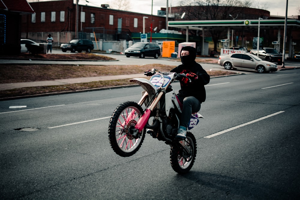 昼間に道路で赤いスポーツバイクに乗る黒いジャケットの女性