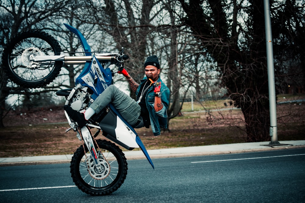 man in black jacket riding blue and white motorcycle