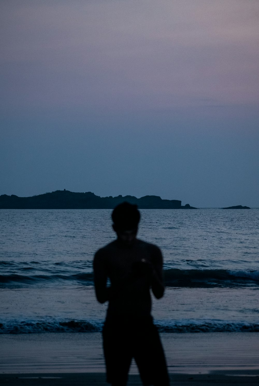 silhouette of man standing on sea shore during daytime