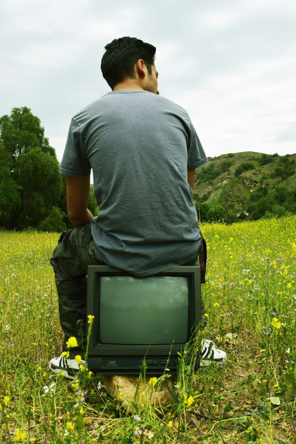 man in gray shirt standing on green grass field during daytime