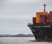 black and red cargo ship on sea under white clouds during daytime