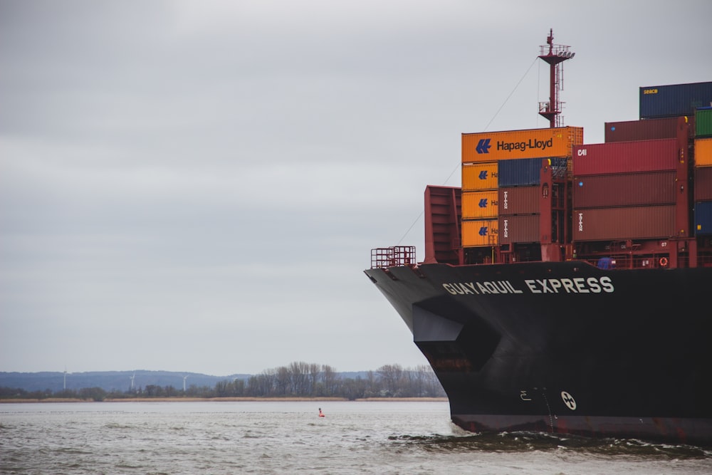 black and red cargo ship on sea under white clouds during daytime