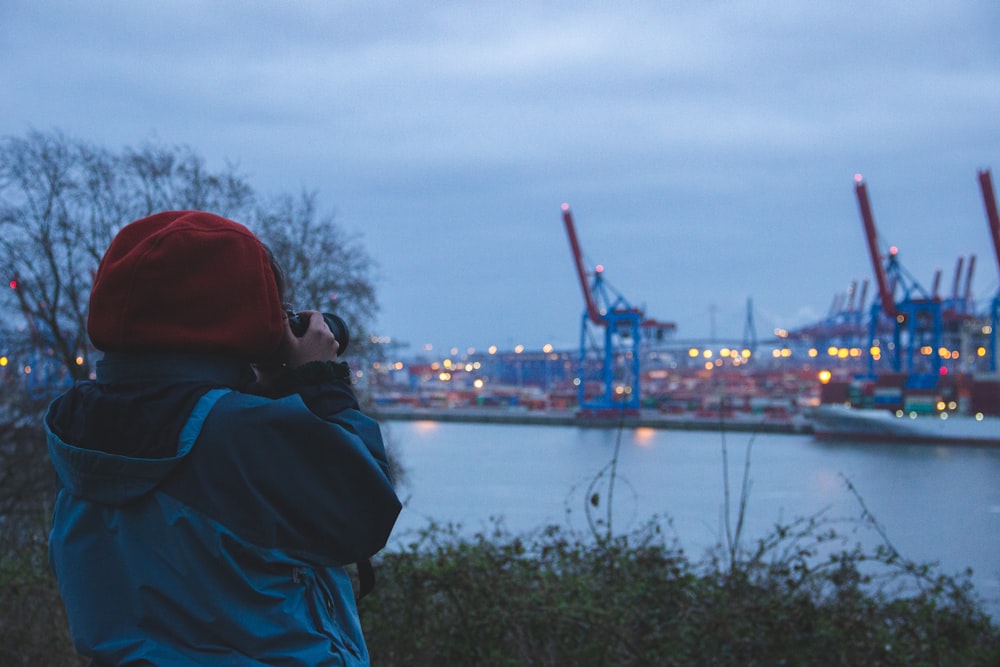 person in red hoodie standing near body of water during night time