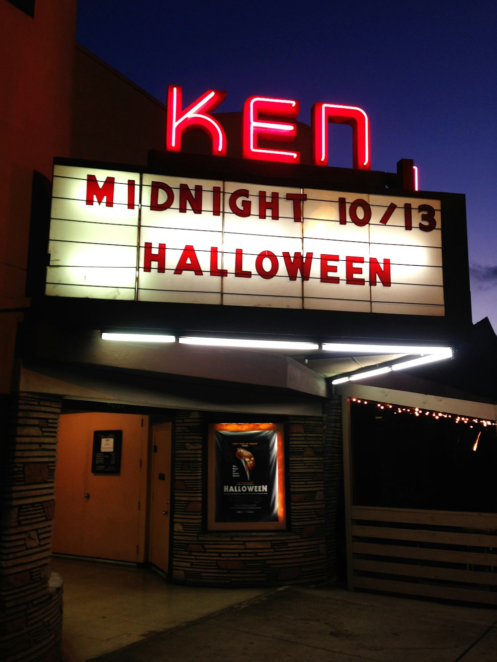 Una carpa de teatro con un letrero iluminado que dice medianoche 101 / 13 halloween