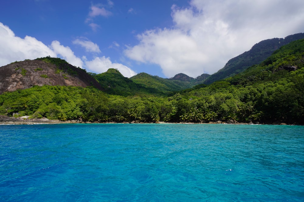 green mountains beside blue sea under blue sky during daytime