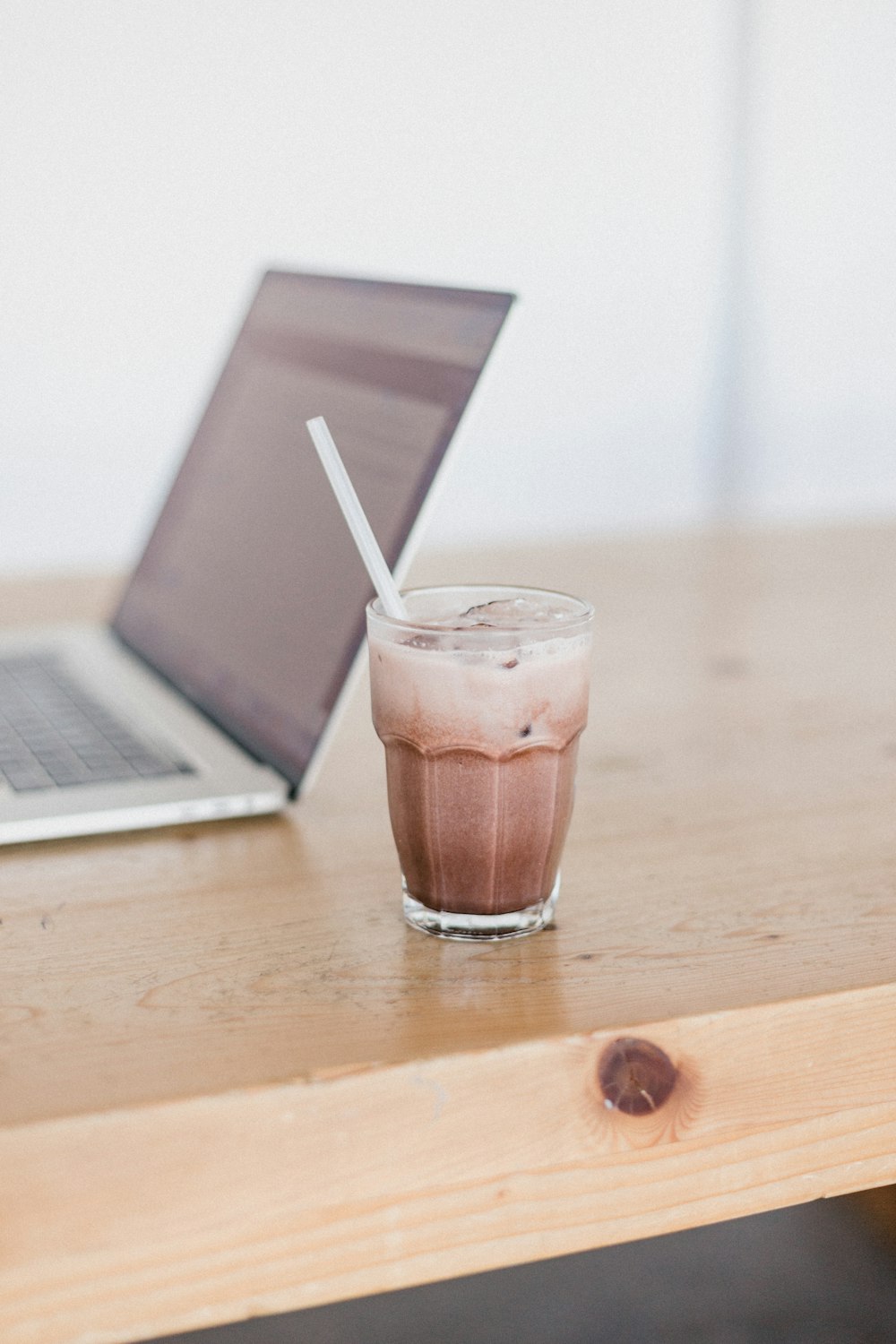 clear drinking glass with brown liquid on brown wooden table