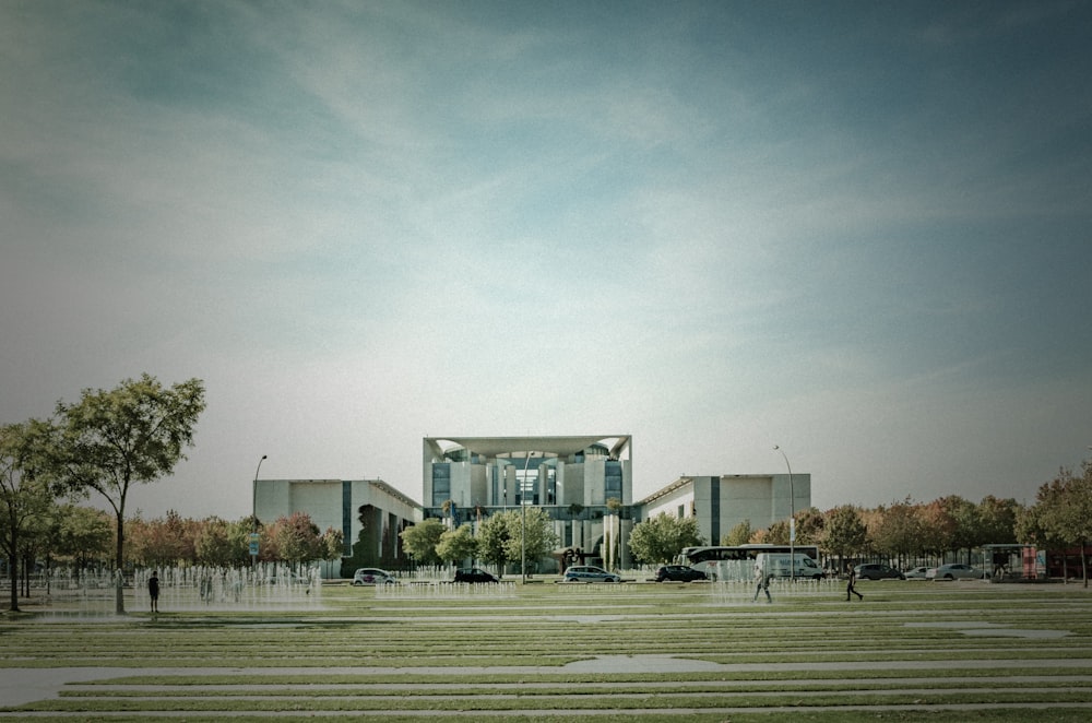 white concrete building near green trees under white clouds during daytime