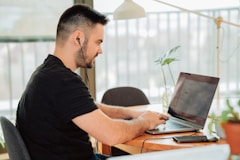 man in black t-shirt using laptop computer