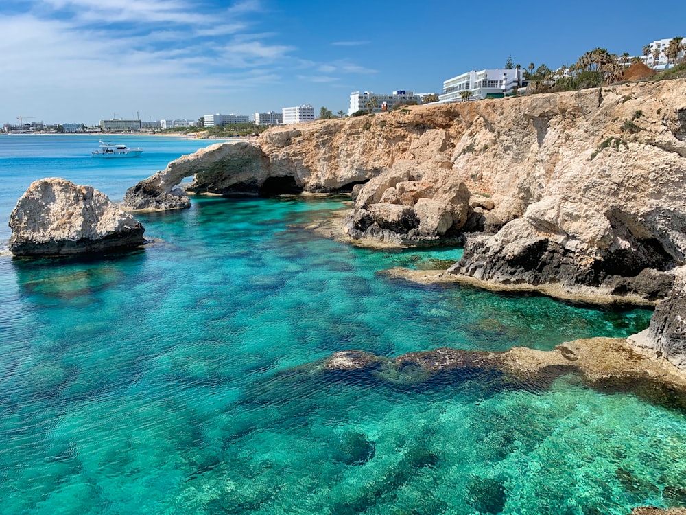 Edificio in cemento bianco sulla formazione rocciosa marrone vicino allo specchio d'acqua durante il giorno